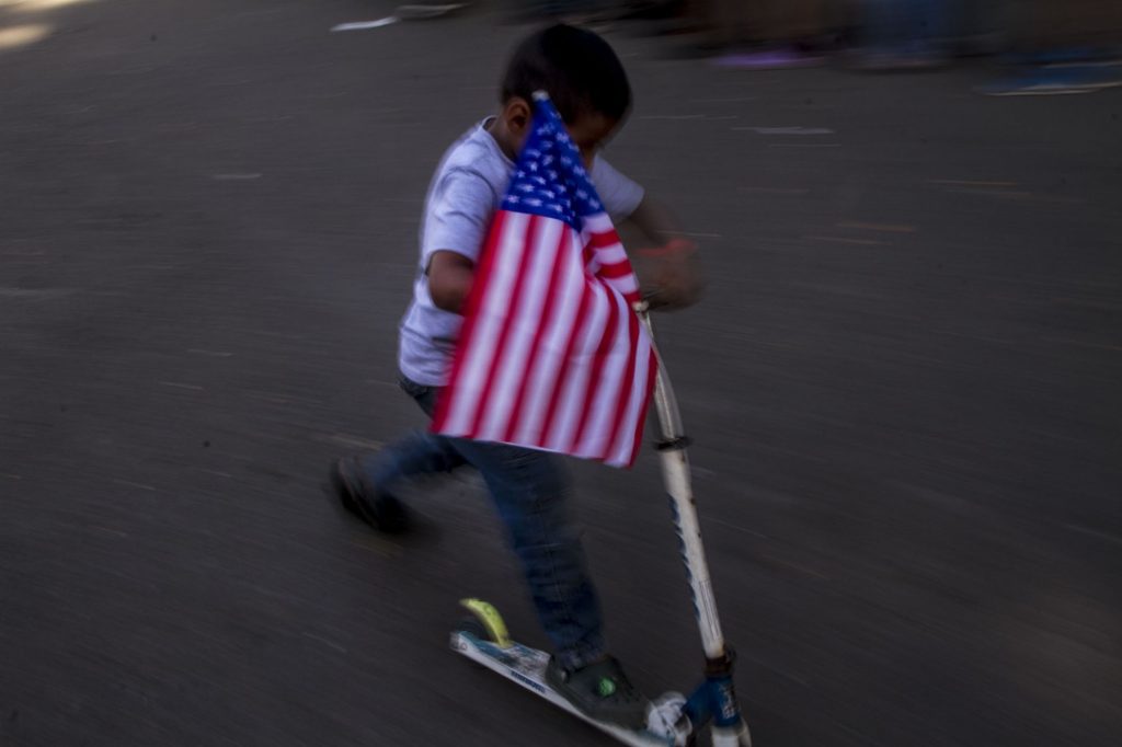  Tijuana Baja California Norte. Emiliano juega con una bandera estadounidense amarrada a su patín del diablo.