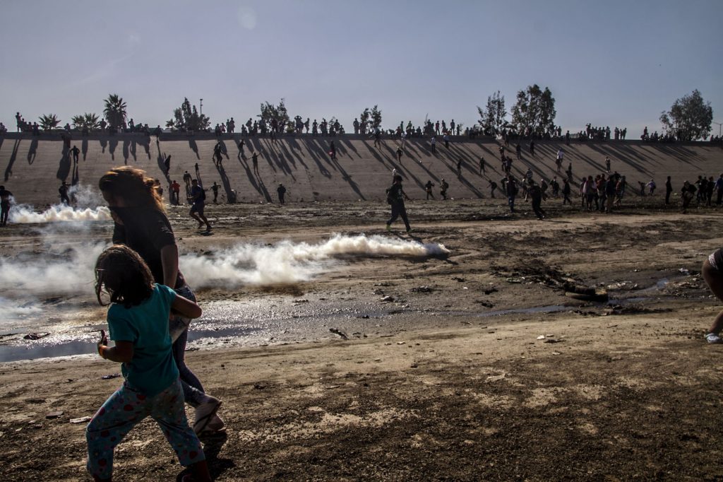 Tijuana, Baja California Norte. A family runs from the tear gas shot by US border patrol agents against the protest by the Central American caravan in Mexico demanding their right to free movement and to seek asylum. Photograph: Ernesto Álvarez
